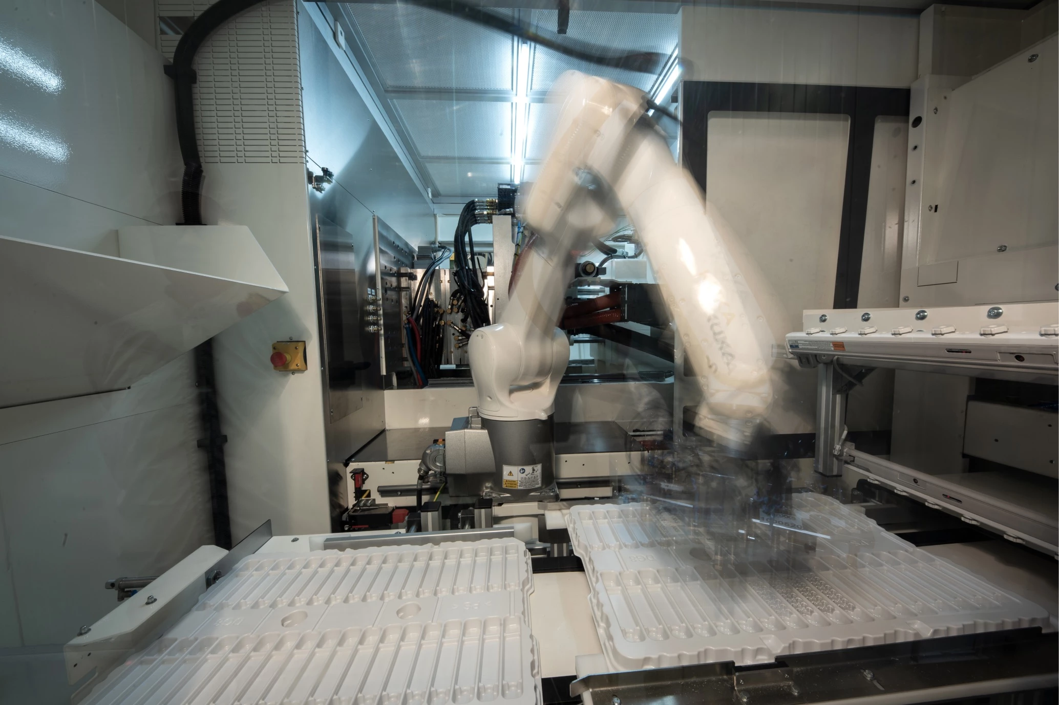 A robotic arm taking a part from a molding machine